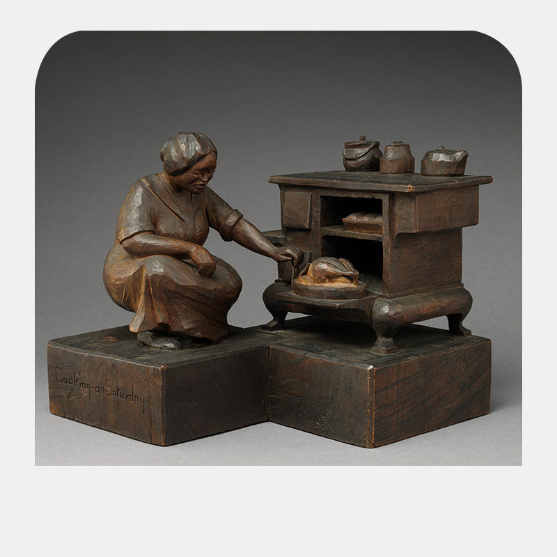 Wooden sculpture of a woman bent at the knees and hunched over an open oven that holds a pot.